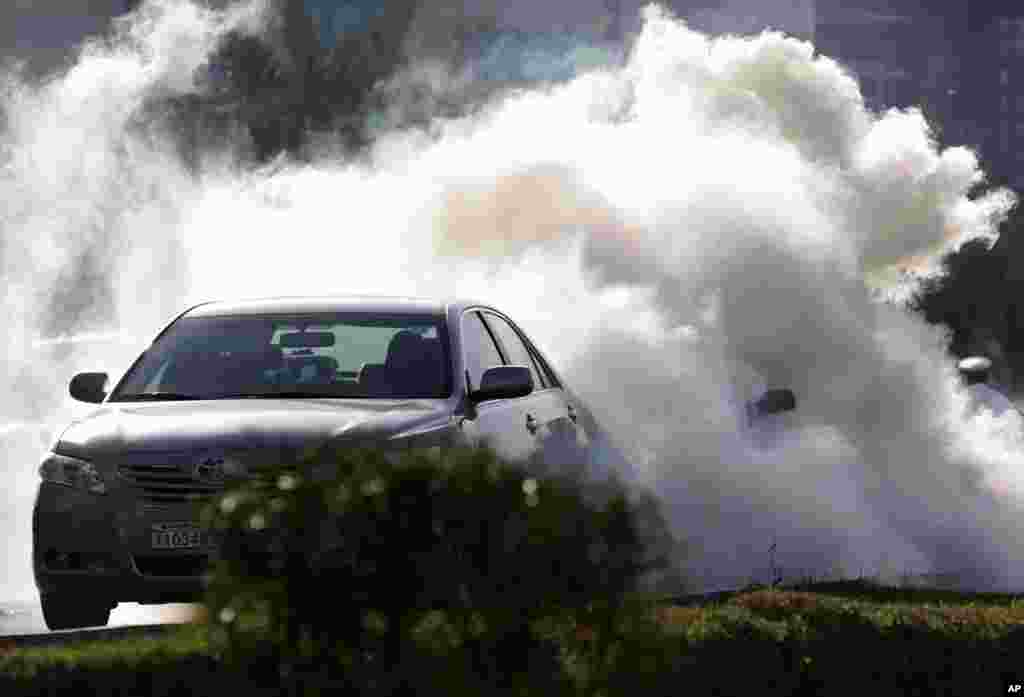 Motorists are caught in a cloud of tear gas fired by riot police at anti-government protesters in Manama during the first anniversary of the pro-democracy uprising in the Gulf kingdom. (AP)