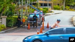 A Judiciary of Guam deputy marshal and a Guam Customs and Quarantine Agency officer monitor a security checkpoint posted in the driveway entrance to the Hyatt Regency Guam in Tumon, April 9, 2020. (Rick Cruz/The Pacific Daily)