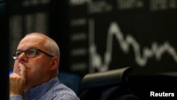 A trader works in front of the German share price index DAX board, at the stock exchange in Frankfurt, Nov. 4, 2015. Frankfurt's DAX index underperformed peers, dragged down by an 8 percent fall in Volkswagen shares.