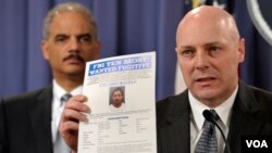 Egzekitif asistan direktè FBI a Shawn Henry kap montre yon papye kriminè leta ameriken ap cheche pandan yon koferans pou laprès nan washington ak Minis jistis ameriken an, Eric Holder