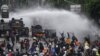 Police officers spray water using a canon to disperse demonstrators during a protest against the government's labour reforms in a polarising jobs creation bill in Jakarta
