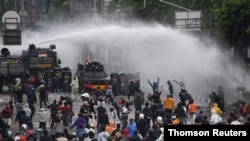 Police officers spray water using a canon to disperse demonstrators during a protest against the government's labour reforms in a polarizing jobs creation bill in Jakarta, Oct. 8, 2020.