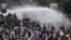Police officers spray water using a canon to disperse demonstrators during a protest against the government's labour reforms in a polarising jobs creation bill in Jakarta