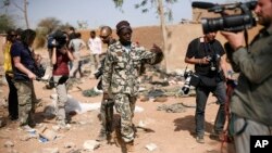 A Malian soldier gestures at journalists to leave the area of a French air strike. Image was taken during an official visit organized by the Malian army to the town of Konna, north of Mali's capital Bamako, January 26, 2013. 