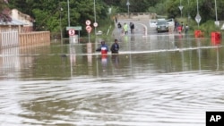 FILE- People wade through flood waters in Ladysmith, KwaZulu Natal Province Monday, Jan 17, 2022.