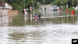 FILE: In an earlier weather disaster in KwaZulu Natal, People wade through flood waters in Ladysmith, KwaZulu Natal Province on Mon. Jan 17, 2022. 