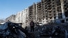 Un residente local se encuentra junto a los restos de su automóvil en el patio de un edificio de apartamentos destruido en el transcurso del conflicto entre Ucrania y Rusia en la ciudad portuaria asediada de Mariúpol, Ucrania, el 28 de marzo de 2022.