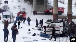 This handout photo provided by Russia Emergency Situations Ministry press service shows Emergency Situations employees and police working at the side of the bus after plunging from a bridge over the Kuenga River, about 4900 kilometers (3100 miles)…