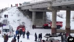 This handout photo provided by Russia Emergency Situations Ministry press service shows Emergency Situations employees and police working at the side of the bus after plunging from a bridge over the Kuenga River, Dec. 1, 2019.. 