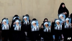 Des manifestants brandissent des photos du plus haut dignitaire chiite de Bahreïn, cheikh Issa Qassem, pour lui manifester leur soutien, à Karrana, Bahreïn, le 17 mai 2013.