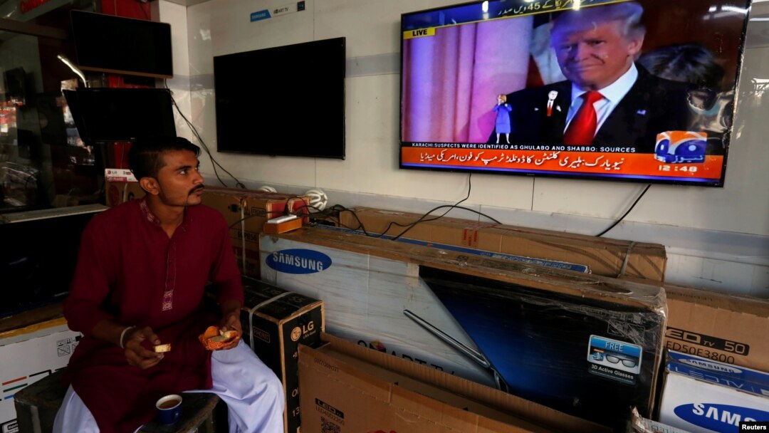 Seorang pedagang di Karachi, Pakistan, makan pagi sambil menonton berita soal Donald Trump. (Foto: Dok)