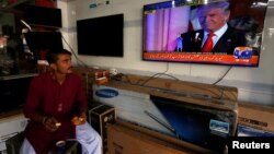 FILE - A salesman in Karachi, Pakistan, eats breakfast as he watches Donald Trump's November 9, 2016 victory speech.