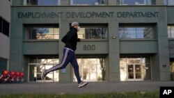 FILE — In his Dec. 18, 2020 file photo a runner passes the office of the California Employment Development Department in Sacramento, Calif. 