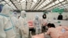 2022年4月9日，中国上海，身穿防护服的医务人员在上海新国际展览馆进行查房时检查一名儿童患者，该馆已变成冠状病毒病 (COVID-19) 的临时医院。