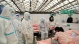 2022年4月9日，中国上海，身穿防护服的医务人员在上海新国际展览馆进行查房时检查一名儿童患者，该馆已变成冠状病毒病 (COVID-19) 的临时医院。