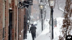 Un hombre con una pala intenta limpiar una acera en Beacon Hill, Boston.