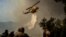 A firefighting helicopter drops water drop as a wildfire burns in the village of Pyrgos, near Corinth, Greece, on September 30, 2024.