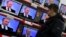 A person watches a live television broadcast showing Russian Prime Minister Vladimir Putin attending a national call-in TV show as it is shown on several screens at a store in Moscow, Russia, Thursday, Dec. 15, 2011. Putin said Thursday the results of Rus