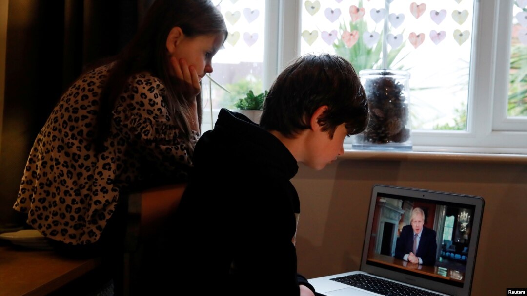 Noah aged 10 and Milly aged 7 watch Britain's Prime Minister Boris Johnson on a laptop during a broadcast to outline plans for gradually easing lockdown measures following the outbreak of the coronavirus disease (COVID-19), Hertford, Britain, May 10, 2020