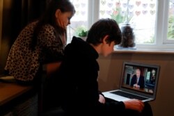 Noah aged 10 and Milly aged 7 watch Britain's PM Boris Johnson on a laptop during a broadcast to outline plans for gradually easing lockdown measures following the outbreak of the coronavirus disease (COVID-19), Hertford, Britain, May 10, 2020.