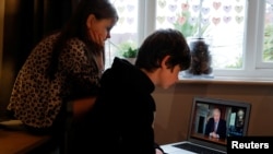 Noah aged 10 and Milly aged 7 watch Britain's Prime Minister Boris Johnson on a laptop during a broadcast to outline plans for gradually easing lockdown measures following the outbreak of the coronavirus disease (COVID-19), Hertford, Britain, May 10, 2020