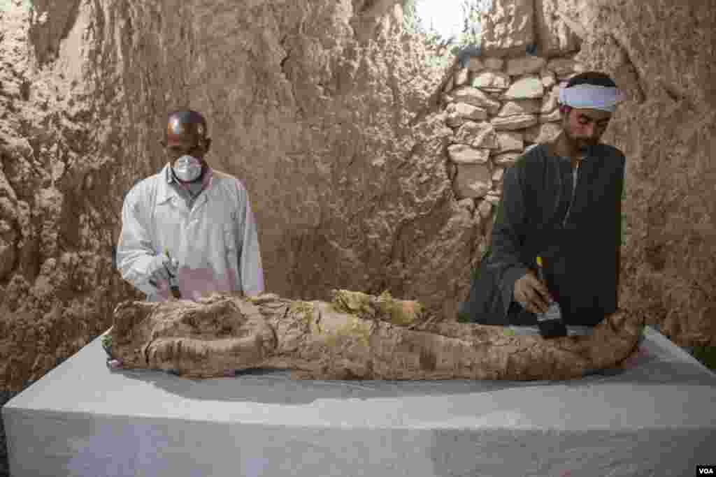 Pekerja penggalian menggali mumi dari makam yang baru ditemukan, atau dikenal dengan Kampp 150 di pekuburan Draa Abul Naga di Tepi Barat Luxor, Mesir, 9 Desember 2017. (H. Elrasam/VOA)