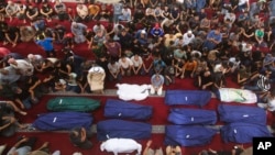 FILE - Mourners pray by the bodies of Salem Abu Quta family members, a Hamas fighter, during a funeral after they were killed in an Israeli strike on their house in Rafah refugee camp, southern Gaza Strip, October 8, 2023. 