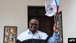 FILE - Tundu Lissu, the presidential candidate of Tanzania's main opposition Chadema party, poses with his party's flag as he speaks to the media at his home in Dar es Salaam, Tanzania, Sept. 9, 2020. 