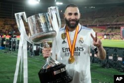 Karim Benzema berpose dengan memegang trofi setelah Madrid mengalahkan Osasuna 2-1 dalam final sepak bola Copa del Rey di stadion La Cartuja di Seville, Spanyol, Sabtu, 6 Mei 2023. (Foto: AP/Jose Breton)