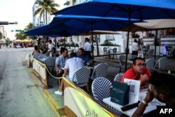 FILE - People eat in an outdoor dining area of a restaurant in Miami Beach, Florida, June 24, 2020.