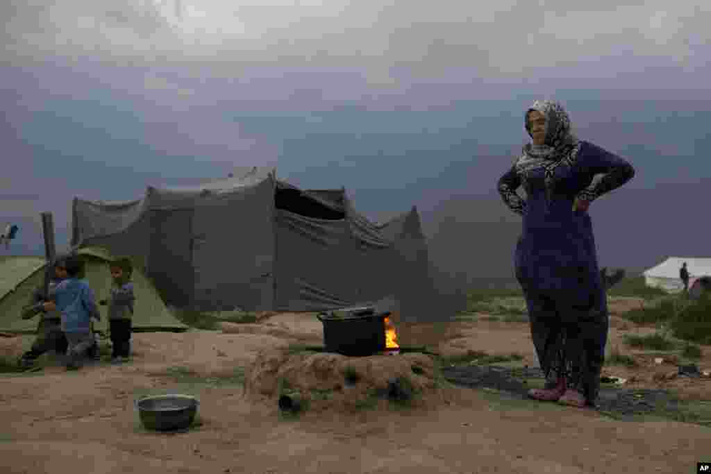 A Syrian woman cooks at the northern Greek border point of Idomeni, Greece.