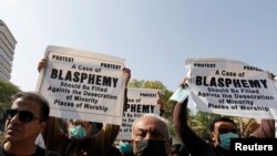 People from the Hindu community hold signs to condemn the attack on a century-old Hindu temple in northwestern Pakistan, during a protest outside Supreme Court building in Karachi, Pakistan, Dec. 31, 2020. 