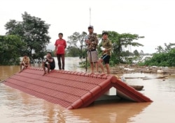 FILE - Villagers take refuge on a rooftop above floodwaters from a collapsed dam in the Attapeu district of southeastern Laos, July 24, 2018.