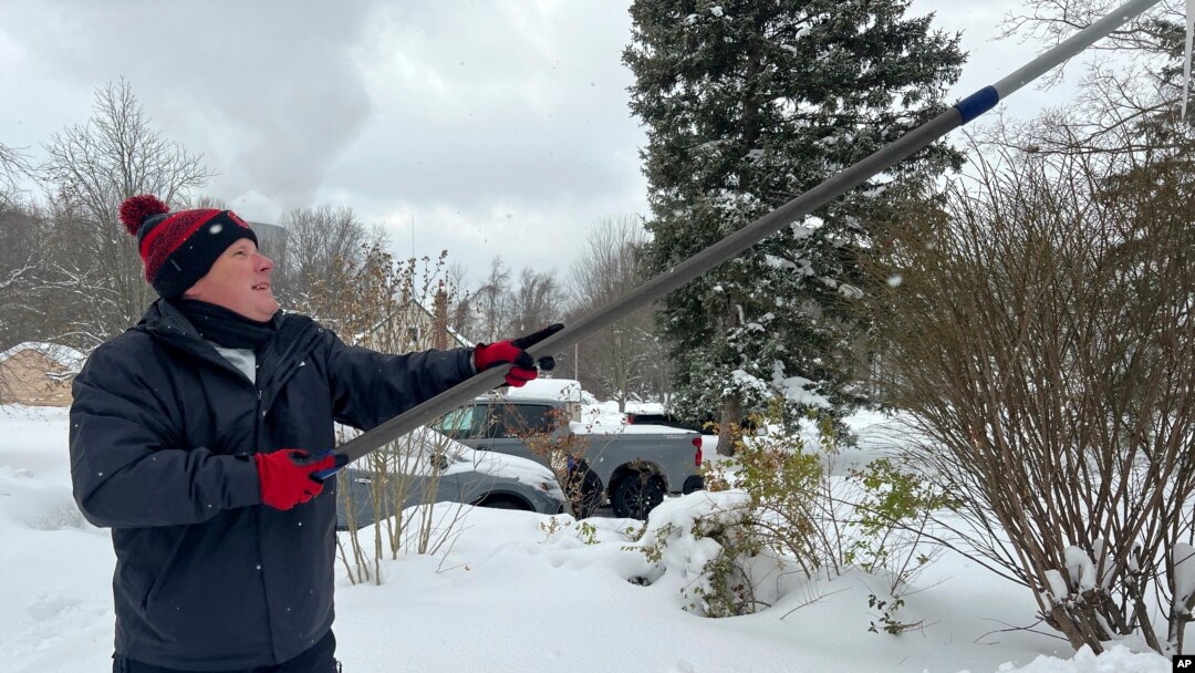 ARCHIVO - Una persona despeja la nieve del techo de su casa en North Perry, Ohio el 3 de diciembre del 2024. (AP foto/Patrick Aftoora-Orsagos).