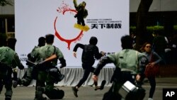 Policías antimotines persiguen a un hombre enmascarado antes de una marcha pidiendo reformas democráticas y un boicot al Partido Comunista chino en Hong Kong, el domingo 19 de enero de 2020. (AP Foto/Ng Han Guan)