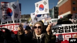 Seorang wanita melambaikan bendera Korea Selatan dan Amerika Serikat selama unjuk rasa untuk mendukung presiden Korea Selatan yang dimakzulkan Yoon Suk Yeol, di dekat kediaman presiden di Seoul Kamis 2 Januari 2025. 