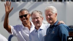 Los expresidentes de EE.UU. (izq. a der.) Barack Obama, George W. Bush y Bill Clinton saludan a los espectadores en la Copa Presidentes de Golf en Nueva Jersey, el jueves, 28 de septiembre, de 2017. Junto con George Bush padre y Jimmy Carter, los exmandatarios han lanzado una campaña para ayudar a las víctimas de los huracanes Harvey, Irma y María.