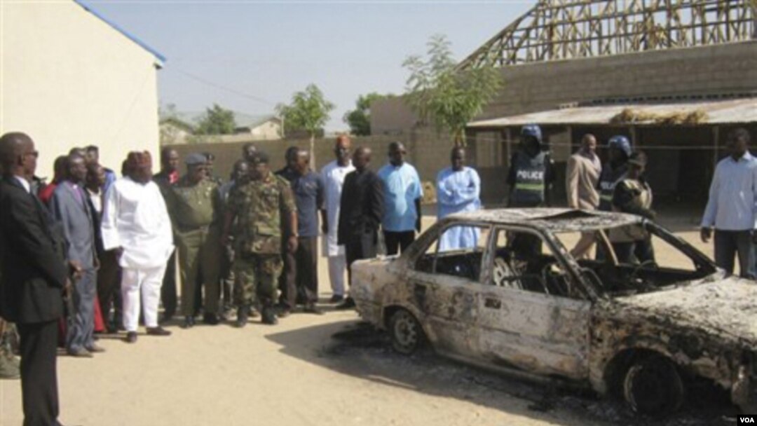 Warga Nigeria mengelilingi sebuah mobil yang terbakar akibat pemboman yang memicu bentrokan antarkelompok bersenjata Kristen dan Muslim.