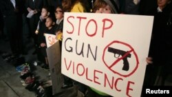 Sophie Bell, 9, holds a sign during an interfaith candlelight prayer vigil to end gun violence in front of Los Angeles City Hall in Los Angeles, California, December 19, 2012.