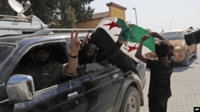 FILE - Members of Turkey-backed Syrian National Army flash the V-sign as they drive back to Turkey near the border between Turkey and Syria, in Akcakale, Sanliurfa province, southeastern Turkey, Oct. 9, 2019.