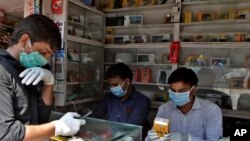 Indian mobile vendors wear protective masks and gloves as a precaution against a new virus at their outlet in Mumbai, India, March 17, 2020. 