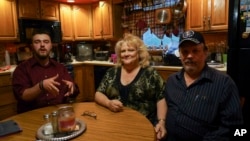 From left, Daniel J. Moore, Lisa Moore and Daniel E. Moore pose for a picture at their kitchen table in Newton Falls, Ohio, Monday, May 1, 2017.