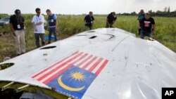 Malaysian and OSCE investigators examine a piece of the crashed Malaysia Airlines Flight 17 in eastern Ukraine, July 23, 2014.