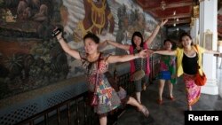 Chinese tourists pose for a picture inside the Grand Palace in Bangkok, May 24, 2014.