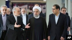 FILE - President Hassan Rouhani (center) listens to head of Iran's Atomic Energy Organization Ali Akbar Salehi (left) while attending a ceremony marking the national day of nuclear technology in Tehran, Iran, Thursday, April 7, 2016. Iran's Health Minister Hassan Ghazizadeh Hashemi is at right.