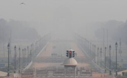 People walk near India Gate on a smoggy afternoon in New Delhi, India, Nov. 15, 2020.