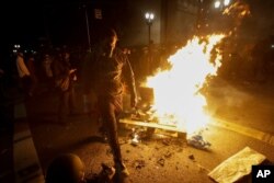 A protester walks past a bonfire set at an intersection during a Black Lives Matter protest at the Mark O. Hatfield United States Courthouse July 25, 2020, in Portland, Ore.