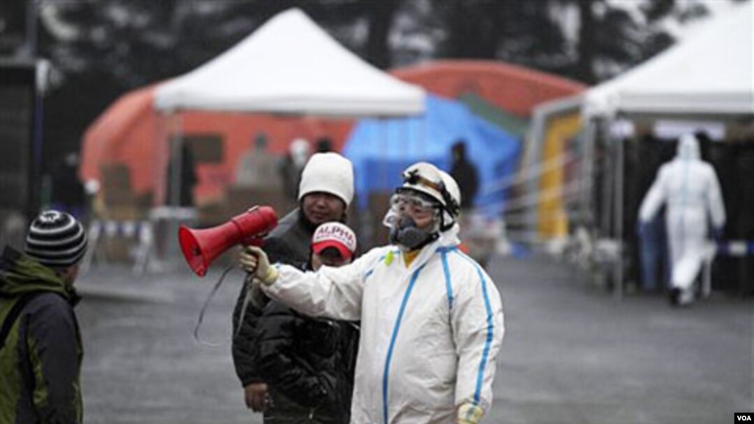 Petugas di Fukushima mengenakan baju khusus anti-radiasi, Selasa (15/3).