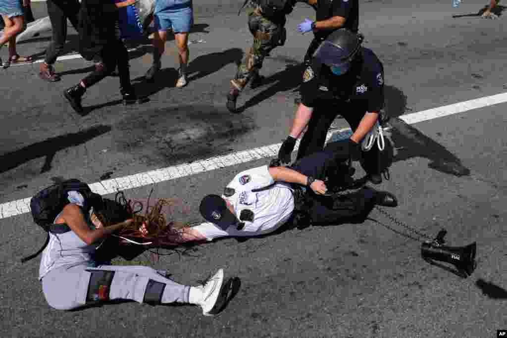 A Black Lives Matter protester and NYPD officers scuffle on the Brooklyn Bridge during a demonstration, in New York, July 15, 2020.