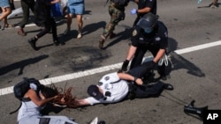 A Black Lives Matter protester and NYPD officers scuffle on the Brooklyn Bridge during a demonstration, in New York, July 15, 2020.